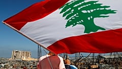مردی با در دست داشتن پرچم لبنان به ویرانه‌های ناشی از ��نفجار بیروت می‌نگرد