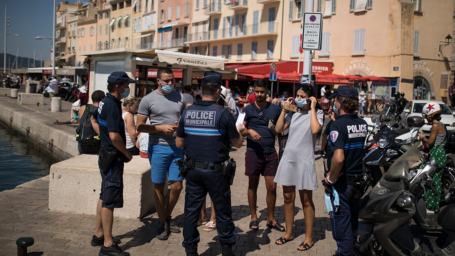 Police give masks to tourists walking along the Saint-Tropez port.