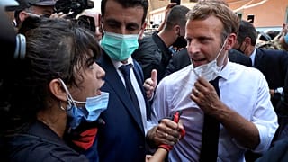 French President Emmanuel Macron, right, speaks with a woman as he visits the Gemayzeh neighborhood, which suffered extensive damage from the explosion in Beirut.