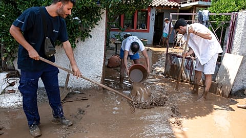 Un grupo de vecinos limpian los bajos de su casa en la isla de Eúbea (Grecia)