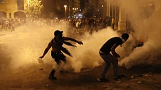 A protester turns back tear gas canister against the Lebanese riot police