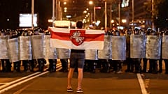 Un manifestant face aux policiers avec l'ancien drapeau du Bélarus, à Minsk, le 9 août 2020, Bélarus