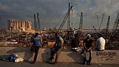 People sit near the site of last week's explosion that hit Beirut's port