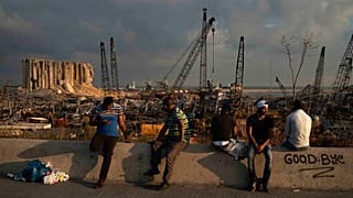 People sit near the site of last week's explosion that hit Beirut's port