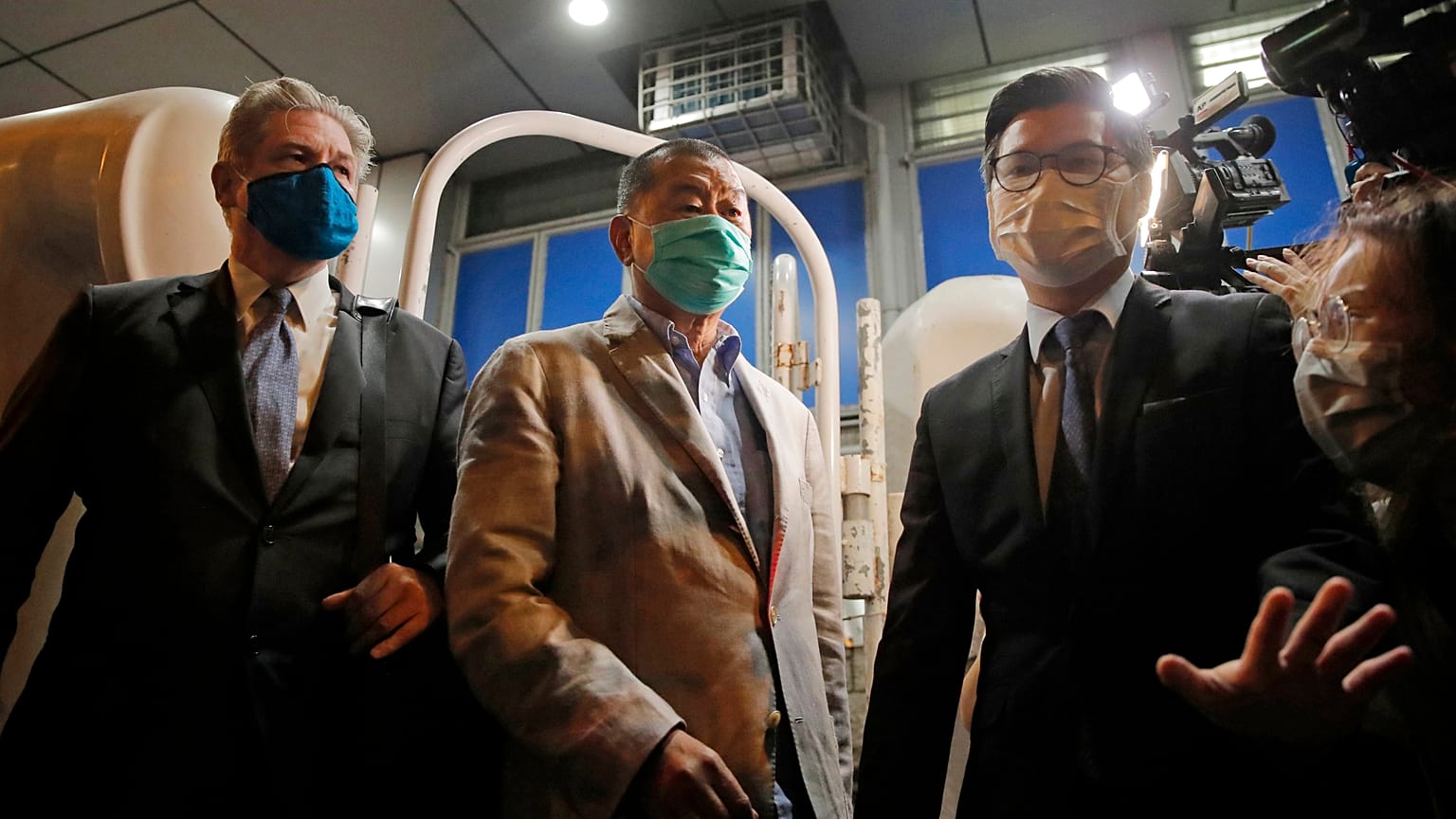 Hong Kong media tycoon and newspaper founder Jimmy Lai, center, walks out from a police station after being bailed out in Hong Kong