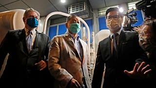 Hong Kong media tycoon and newspaper founder Jimmy Lai, center, walks out from a police station after being bailed out in Hong Kong