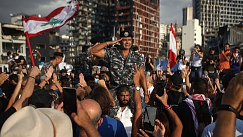 A crowd cheers members of the Lebanese Civil Defence during a commemoration ceremony for the victims of the Beirut port explosion.