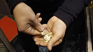 An Iranian goldsmith counts his gold coins at a gold market in the main old Bazaar of Tehran, Iran