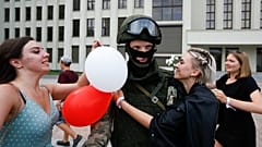 Mujeres abrazan a un soldado que vigila el edificio del Gobierno en Minsk en una protesta pacífica conra la represión policial