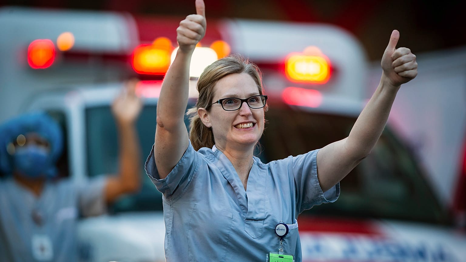 A healthcare worker at St. Paul's Hospital acknowledges applause and cheers from people outside the hospital