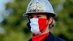 a firefighter wears a face mask with the colors of the French flag, prior to the Bastille Day parade 
