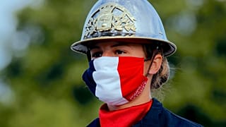 a firefighter wears a face mask with the colors of the French flag, prior to the Bastille Day parade