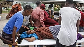People help a civilian woman, who was wounded when a powerful car bomb blew off the security gates to the Elite Hotel, in Somalia Sunday, Aug. 16, 2020.