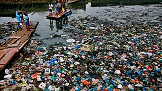 Oct. 2, 2016 file photo: a man guides a raft through a polluted canal littered with plastic bags and other garbage in Mumbai, India. 