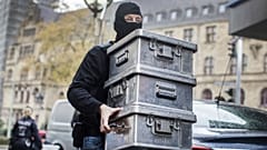 Police carry boxes after investigations at a jeweler in Duisburg-Marxloh, western Germany