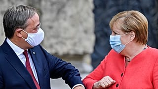 Канцлер Германии Ангела Меркель здоровается с премьер-министром федеральной земли Северный Рейн-Вестфалия. 