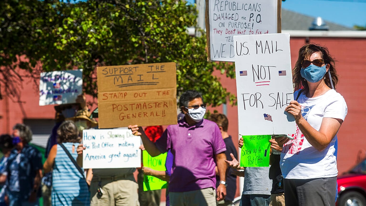 gather in front of the United States Post Office to protest recent changes to the USPS under new Postmaster General Louis DeJoy, Tuesday, Aug. 11, 2020 in Midland, Michigan