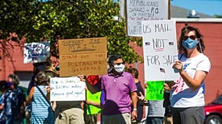 gather in front of the United States Post Office to protest recent changes to the USPS under new Postmaster General Louis DeJoy, Tuesday, Aug. 11, 2020 in Midland, Michigan