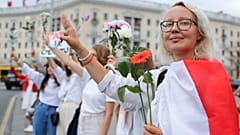 Belarusians protesting against disputed presidential elections results hold flowers and flash victory signs during a protest in Victory Square in Minsk, Belarus. August 20