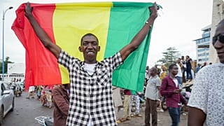 A man holds a national flag as he celebrates with others in the streets in the capital Bamako after a mutiny in Mali.