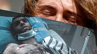 Egy nő egy bántalmazott férfi fotóját tartja az egyik minszki kórház előtt