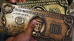Former Russian hacker Sergey Pavlovich holds a mock money printing plate with US President Donald Trump face in place of Benjamin Franklin