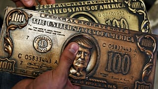 Former Russian hacker Sergey Pavlovich holds a mock money printing plate with US President Donald Trump face in place of Benjamin Franklin