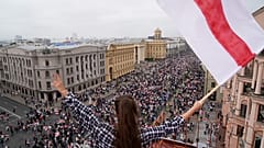 Eine Frau protestiert mit der alten belarussischen Nationalflagge auf einem Dach am Unabhängigkeitsplatz in Minsk