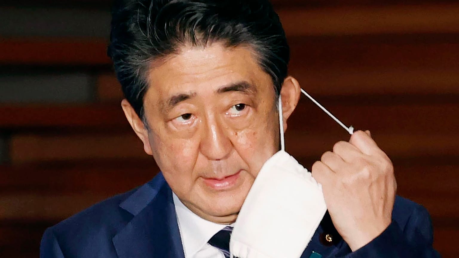 In this May 21, 2020, file photo, Japan's Prime Minister Shinzo Abe removes a face mask as he speaks at a press conference in Tokyo. 