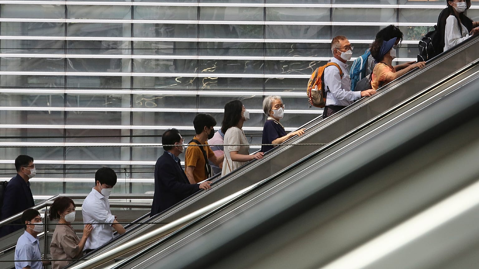 People wearing face masks to help protect against the spread of the coronavirus ride an escalator as they arrive at the Seoul Railway Station in Seoul