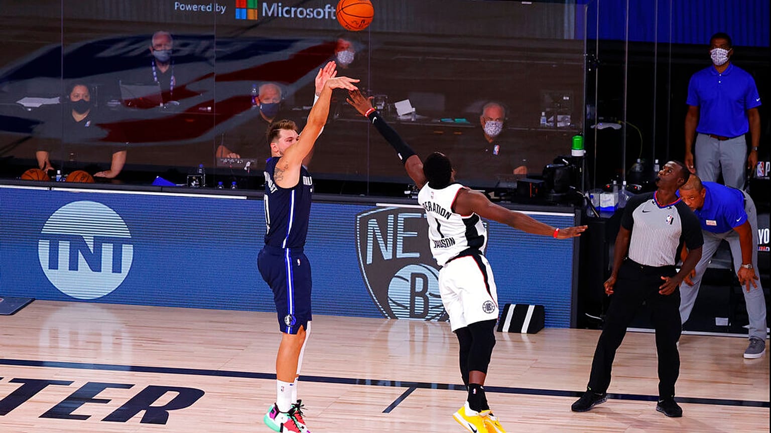 Dallas Mavericks' Luka Doncic, left, hits a winning three-point basket against Los Angeles Clippers' Reggie Jackson.