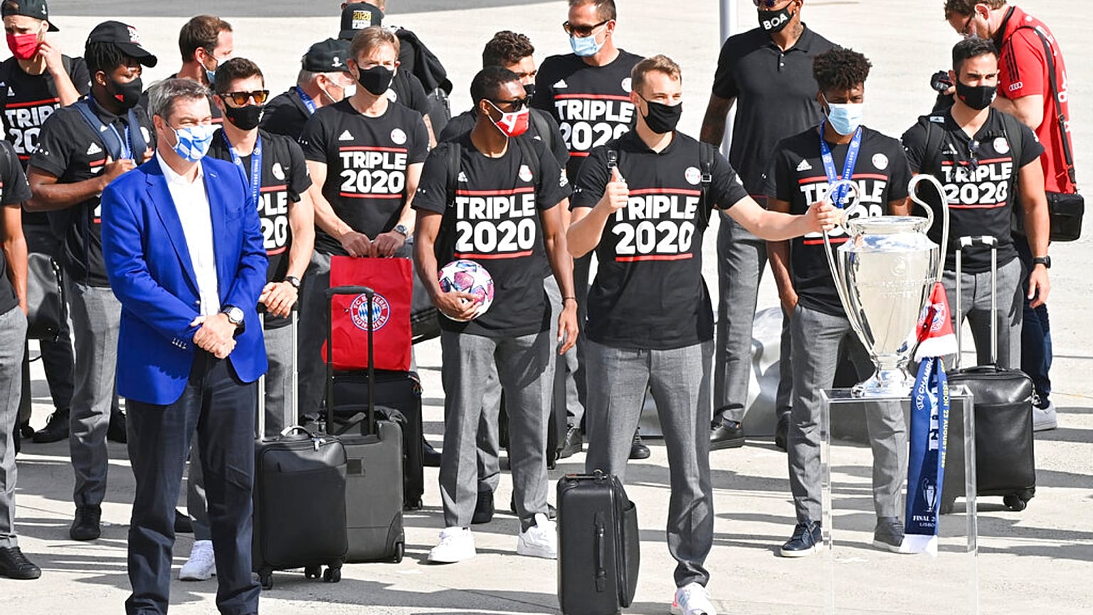 Bavaria Governor Markus Soeder, left, stands with the FC Bayern Munich team after their arrival at Munich Airport, Germany.