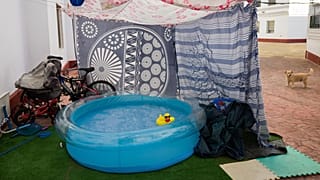 A rubber duck floats in a portable plastic pool that sits in the community housing association patio in Seville, Spain