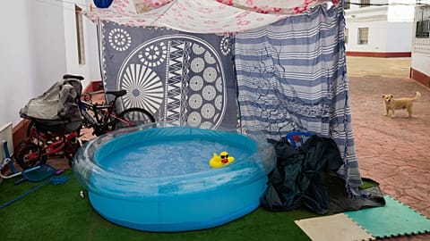 A rubber duck floats in a portable plastic pool that sits in the community housing association patio in Seville, Spain