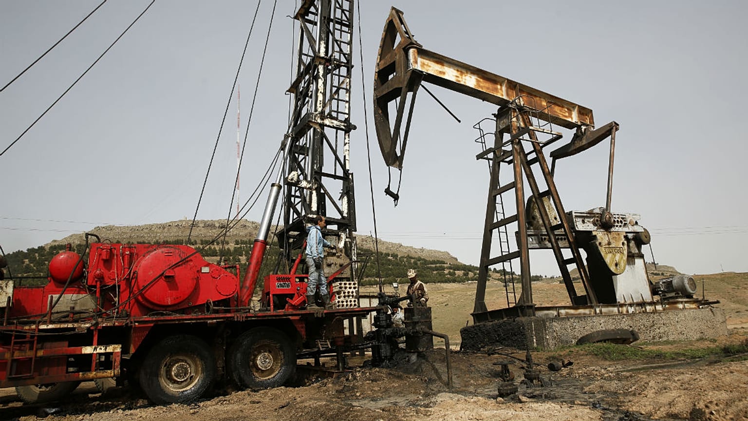 Syrian workers fixing pipes of an oil well at an oil field controlled by a U.S-backed Kurdish group