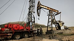 Syrian workers fixing pipes of an oil well at an oil field controlled by a U.S-backed Kurdish group