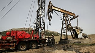 Syrian workers fixing pipes of an oil well at an oil field controlled by a U.S-backed Kurdish group