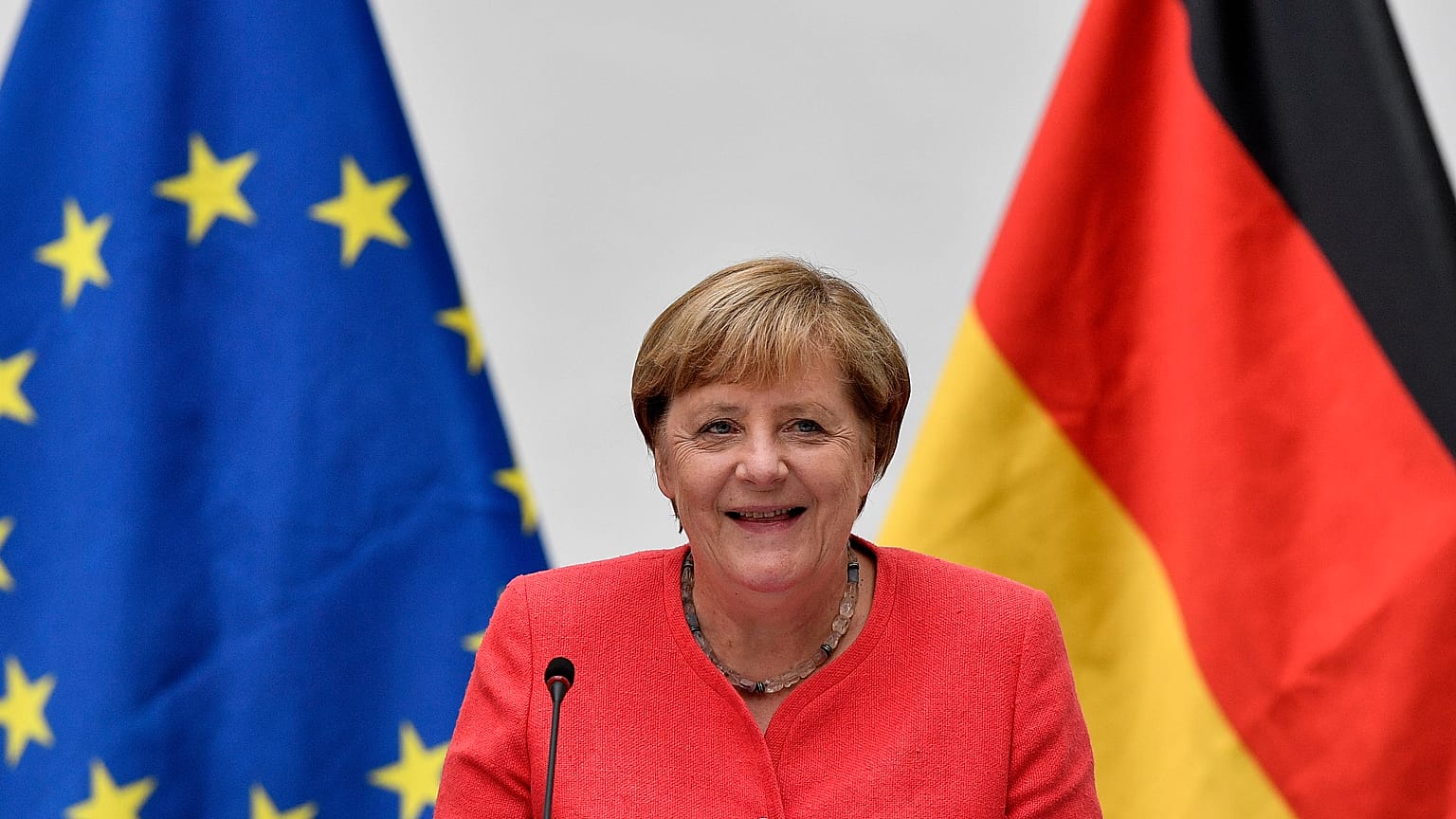 FILE: German chancellor Angela Merkel sits between a European and a German flag in Duesseldorf, Germany, Tuesday, Aug. 18, 2020. 