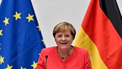 FILE: German chancellor Angela Merkel sits between a European and a German flag in Duesseldorf, Germany, Tuesday, Aug. 18, 2020. 
