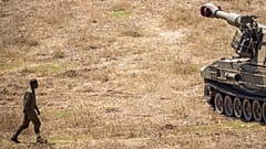 Un soldato israeliano cammina verso un carro armato vicino al confine con il Libano