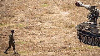 Un soldato israeliano cammina verso un carro armato vicino al confine con il Libano