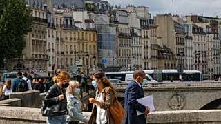 People cross the Petit-Pont-Cardinal-Lustiger bridge while wearing a protective face masks as a precaution against the coronavirus in Paris.
