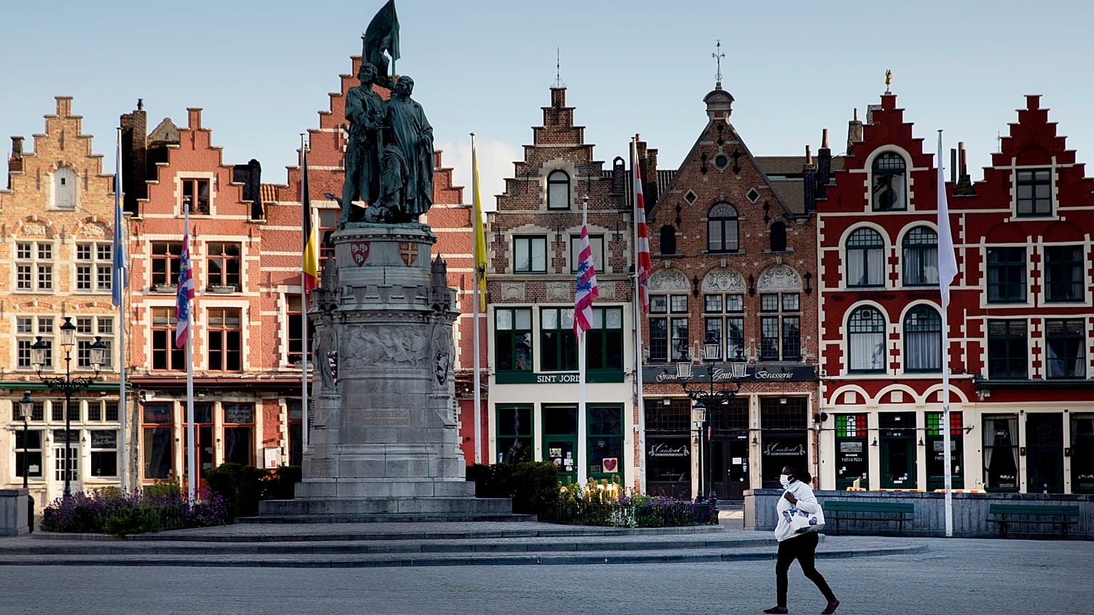A woman wears a mouth mask as she walks in the Market Square in Bruges, Belgium.