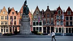 A woman wears a mouth mask as she walks in the Market Square in Bruges, Belgium.
