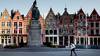 A woman wears a mouth mask as she walks in the Market Square in Bruges, Belgium.