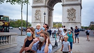 a family wearing protective face masks walk along on the Champs Elysee in Paris.