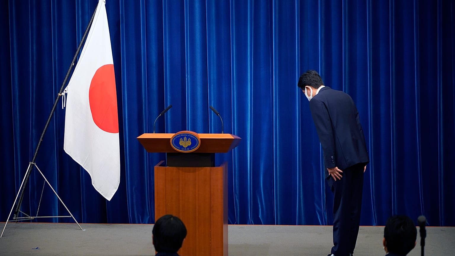 Şinzo Abe, konferans öncesinde Japon bayrağı önünde eğiliyor