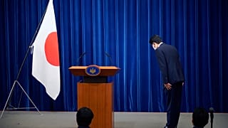 Şinzo Abe, konferans öncesinde Japon bayrağı önünde eğiliyor