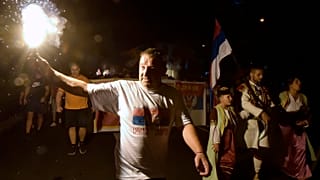 An opposition supporter lights torch during church-led protest in Podgorica, Montenegro, Thursday, Aug. 27, 2020.