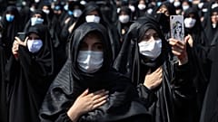 People wearing protective face masks to help prevent spread of the coronavirus mourn during an annual ceremony commemorating Ashoura. 